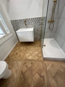 Bathroom refit with oak parquet floor tiles, geometric mosaic wall tiles and brass shower enclosure in South London