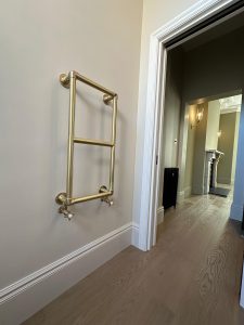 Brass ladder towel rail fitted in period London property with original hallway and oak flooring