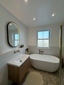 Bathroom renovation with freestanding oval bath, terrazzo floor tiles and oak vanity unit in South London