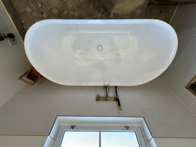 Aerial view of freestanding oval bath with brass floor-mounted tap and terrazzo tiles in South London bathroom