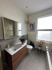 Complete bathroom renovation with walnut floating vanity, green wall tiles and herringbone floor in South London