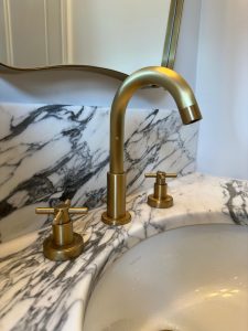 Marble undermount basin with brushed brass cross-handle taps in South London luxury cloakroom