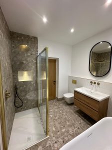 Side view of bathroom renovation with terrazzo shower tiles, brass fittings and floating oak vanity in South London