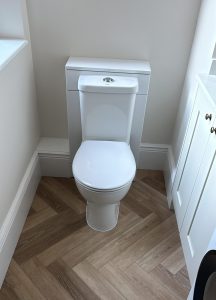 New back-to-wall toilet with herringbone wood-effect floor tiles in South London bathroom refit